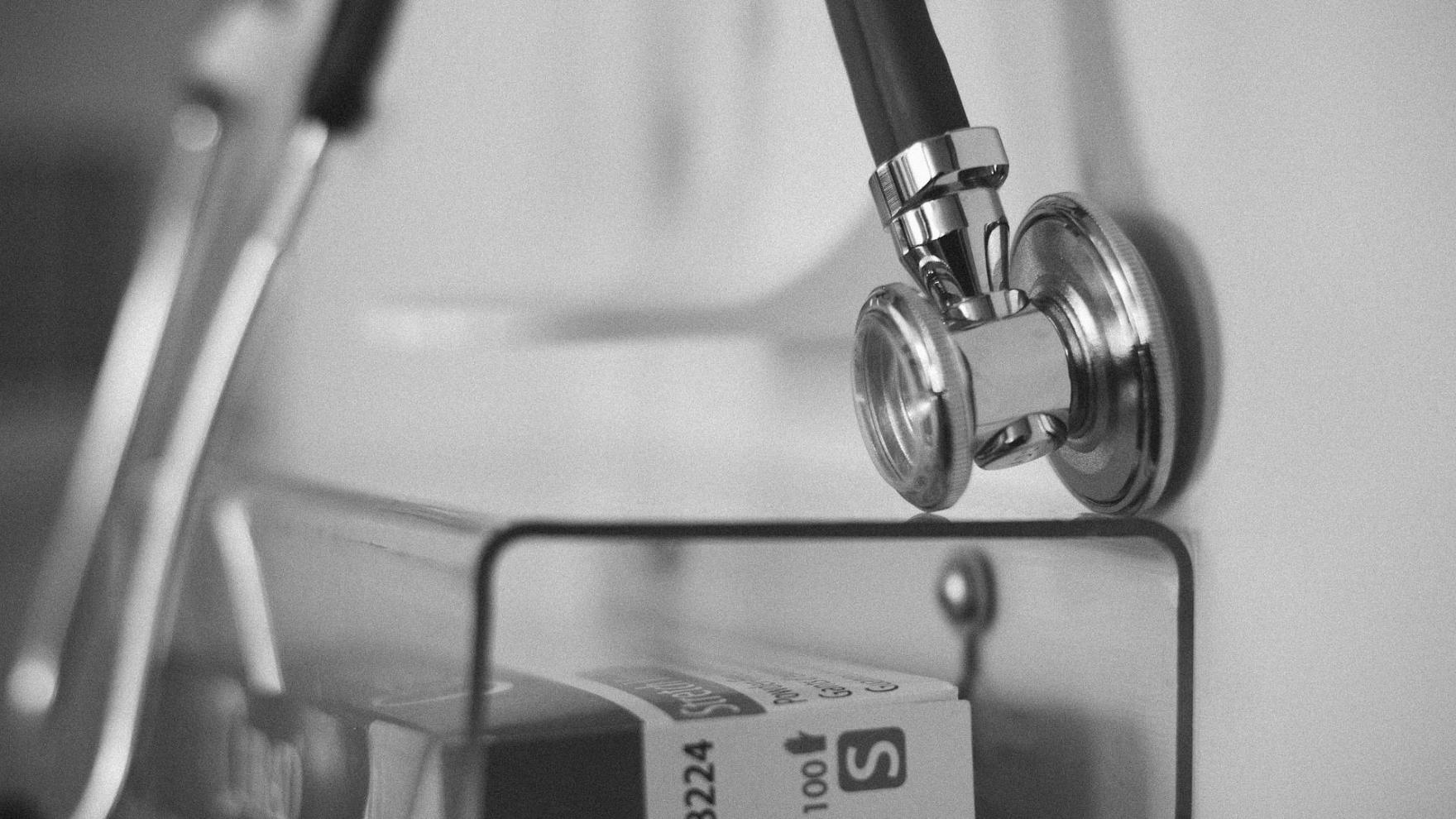 Un stéthoscope posé sur un chariot de soins, en noir et blanc