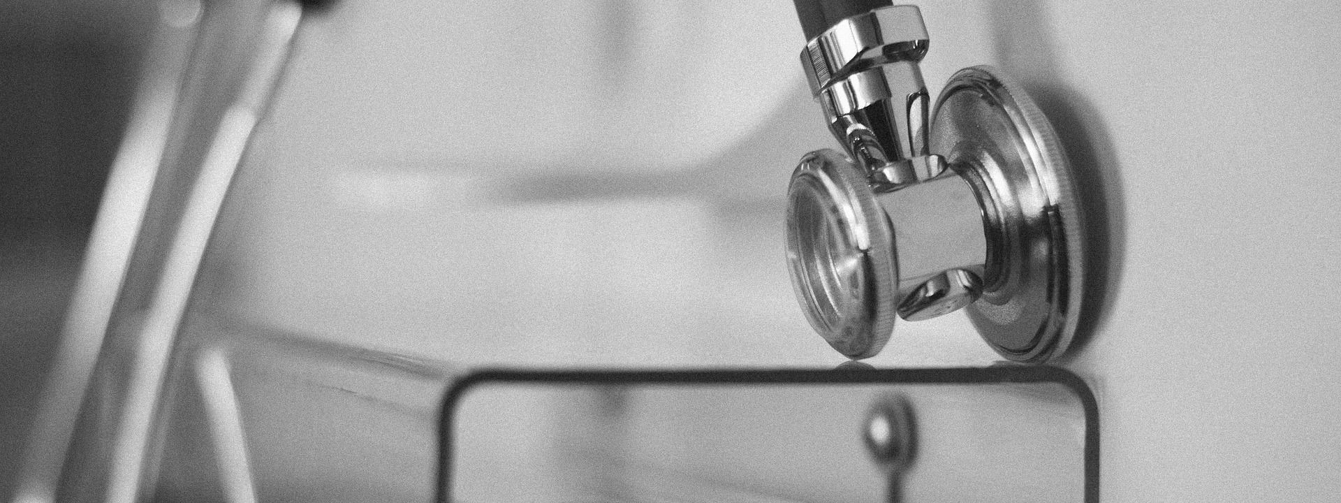 Un stéthoscope posé sur un chariot de soins, en noir et blanc